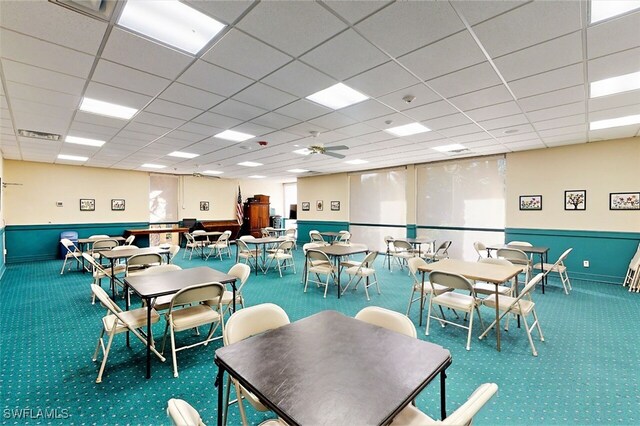 dining area featuring ceiling fan, a drop ceiling, and carpet