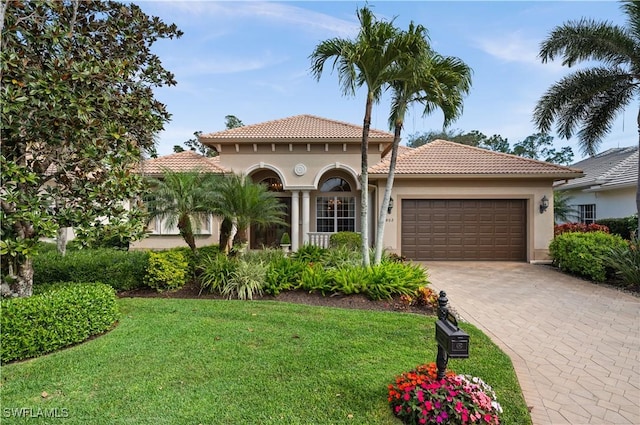 mediterranean / spanish-style home featuring a garage and a front lawn