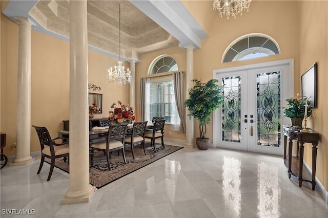 foyer with a chandelier, french doors, decorative columns, and a high ceiling