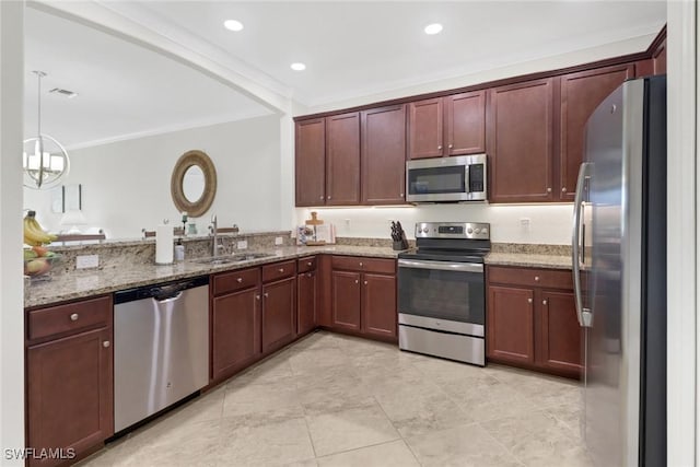 kitchen featuring light stone countertops, sink, decorative light fixtures, and appliances with stainless steel finishes