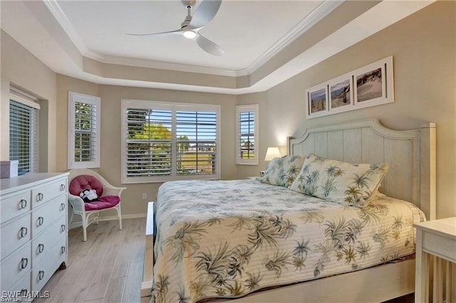 bedroom with ceiling fan, light hardwood / wood-style floors, a raised ceiling, and ornamental molding