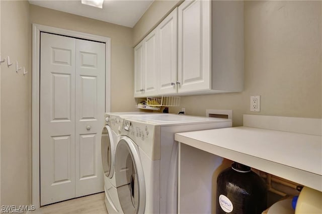 washroom with washer and clothes dryer, cabinets, and light wood-type flooring