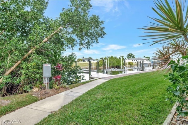 view of home's community with a boat dock and a yard