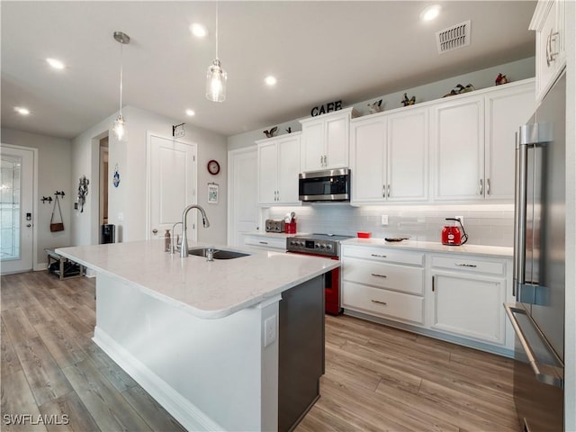 kitchen featuring white cabinets, appliances with stainless steel finishes, hanging light fixtures, and sink