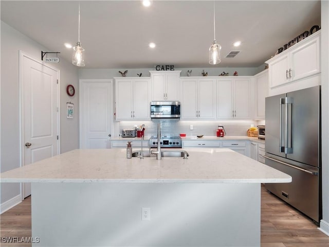 kitchen with white cabinetry, a kitchen island with sink, sink, and appliances with stainless steel finishes