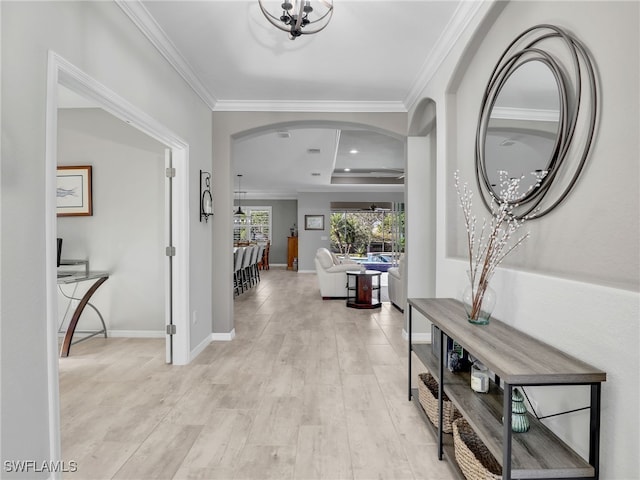 foyer entrance with light wood-type flooring, a raised ceiling, and crown molding