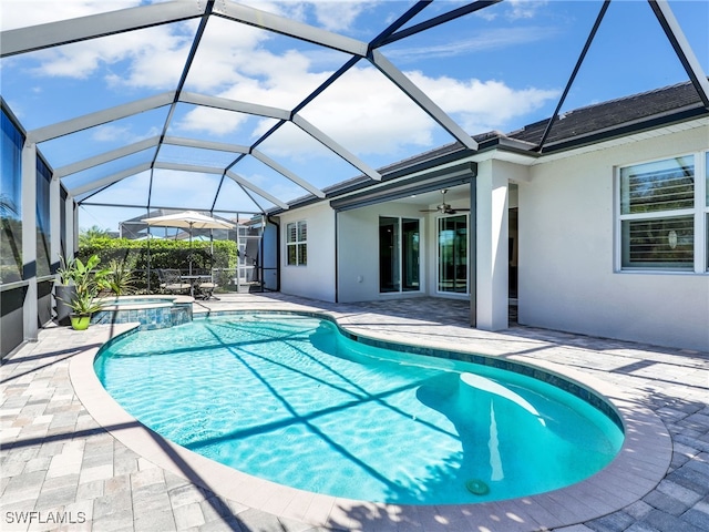 view of pool featuring ceiling fan, a patio, glass enclosure, and an in ground hot tub