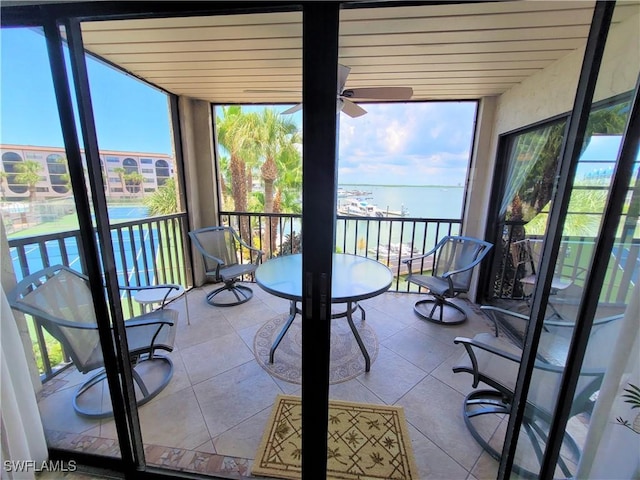 sunroom / solarium with ceiling fan and a water view