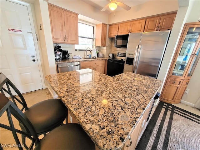 kitchen with light stone countertops, sink, ceiling fan, tasteful backsplash, and appliances with stainless steel finishes