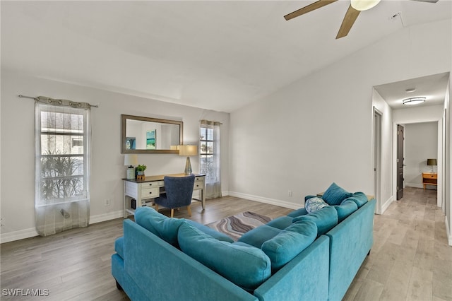 living room with ceiling fan, light hardwood / wood-style floors, and vaulted ceiling