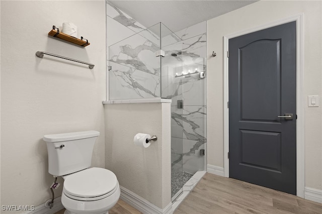 bathroom featuring toilet, a tile shower, and wood-type flooring