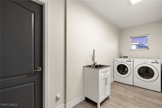 clothes washing area featuring cabinets, independent washer and dryer, light wood-type flooring, and sink