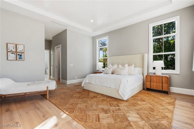 bedroom with a tray ceiling and light hardwood / wood-style floors