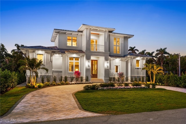 view of front facade featuring decorative driveway, a yard, board and batten siding, a standing seam roof, and metal roof