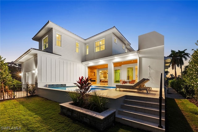 back of house with board and batten siding, fence, a fenced in pool, and a yard