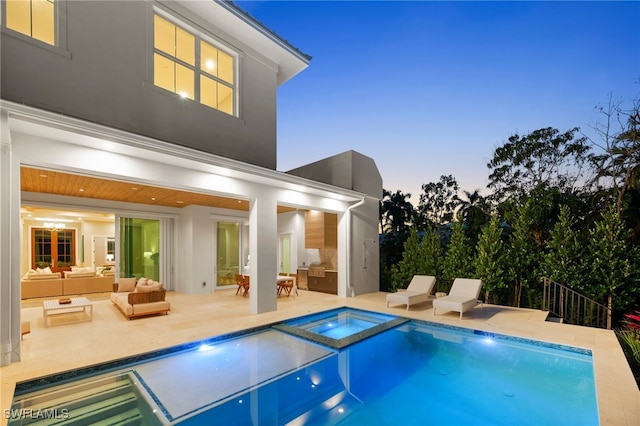 back of property at dusk with an outdoor hangout area, a patio area, a pool with connected hot tub, and stucco siding