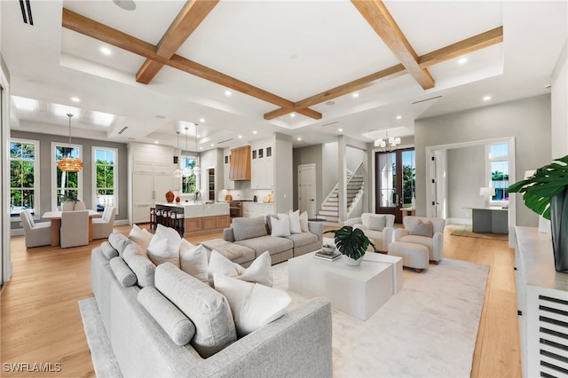 living area with coffered ceiling, beamed ceiling, stairs, light wood-type flooring, and a chandelier