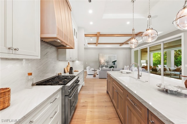 kitchen featuring stainless steel range, white cabinetry, hanging light fixtures, and sink