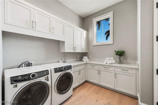 laundry room with cabinets, sink, washer and dryer, and light hardwood / wood-style floors