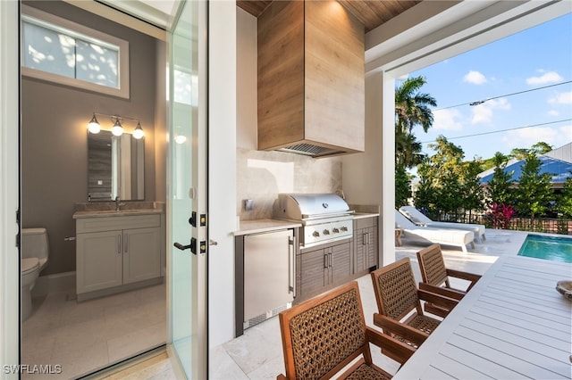 view of patio with a fenced in pool, a grill, sink, and an outdoor kitchen