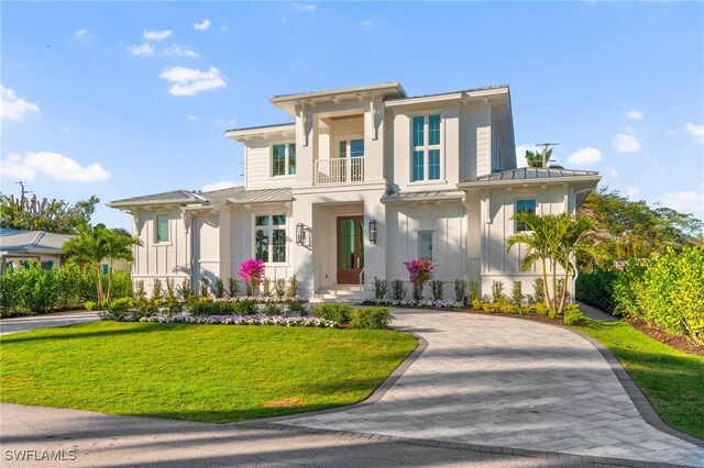 view of front of home with a balcony and a front lawn