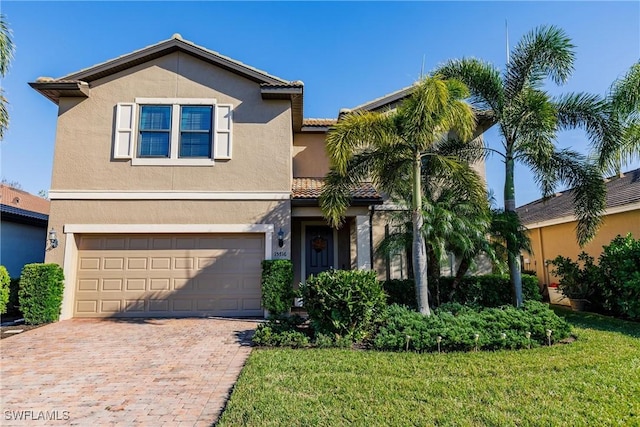 traditional-style home featuring an attached garage, a tile roof, decorative driveway, and stucco siding