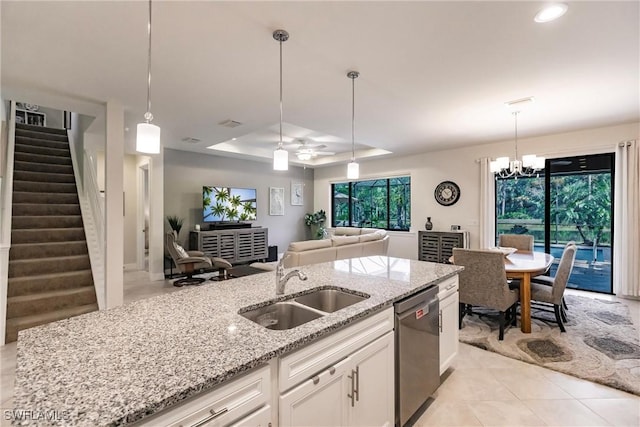 kitchen with a sink, white cabinets, light stone countertops, dishwasher, and a tray ceiling