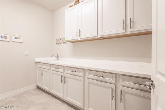 clothes washing area featuring light tile patterned floors, a sink, and baseboards