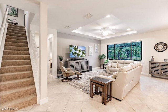 living room featuring light tile patterned floors, recessed lighting, a ceiling fan, stairs, and a tray ceiling