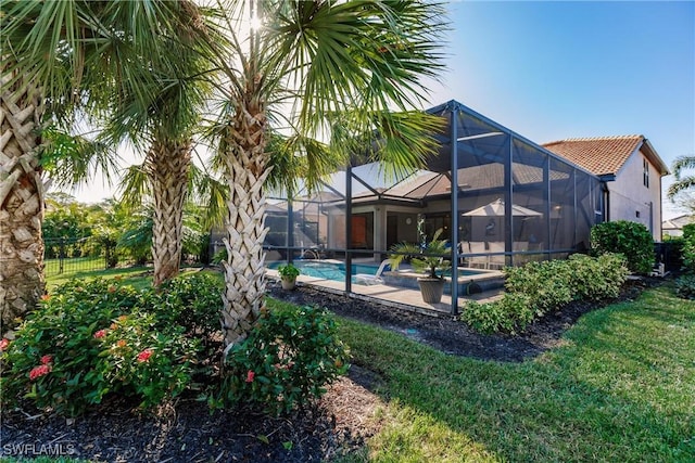 rear view of property with a yard, a patio, and a lanai