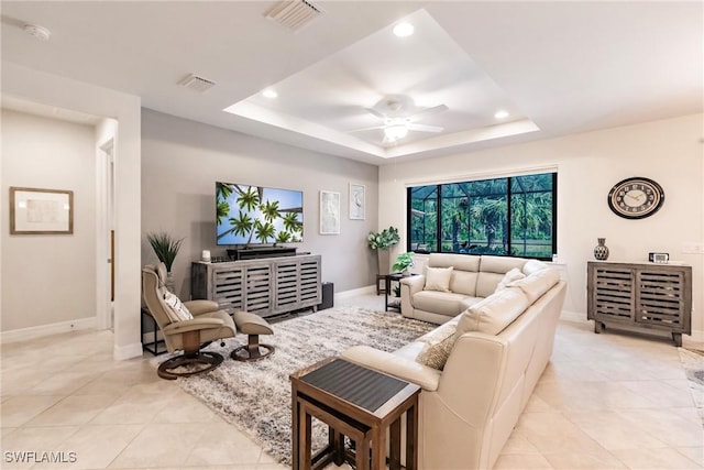 tiled living room with a tray ceiling and ceiling fan