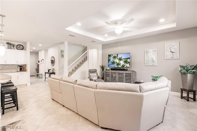 living room featuring ceiling fan, light tile patterned floors, and a tray ceiling