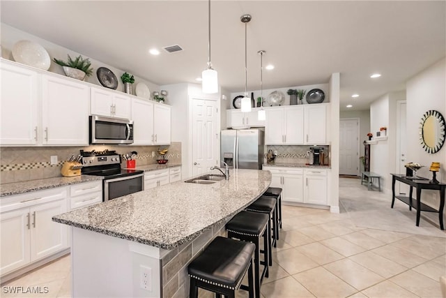 kitchen with a center island with sink, visible vents, white cabinets, appliances with stainless steel finishes, and a sink