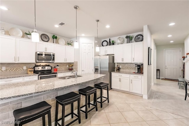 kitchen featuring a kitchen breakfast bar, stainless steel appliances, white cabinetry, and sink