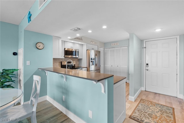 kitchen with kitchen peninsula, white cabinets, and appliances with stainless steel finishes