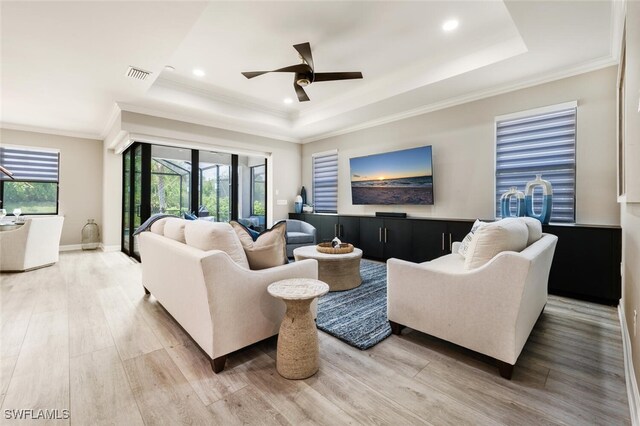 living room featuring wood-type flooring, a tray ceiling, and ceiling fan