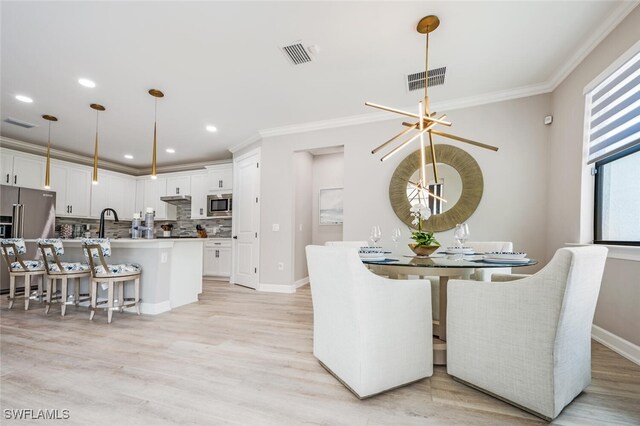 dining space featuring light hardwood / wood-style flooring, a notable chandelier, and crown molding