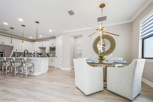 dining room with light wood-style floors, baseboards, visible vents, and crown molding