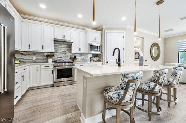 kitchen featuring pendant lighting, sink, an island with sink, white cabinetry, and stainless steel appliances