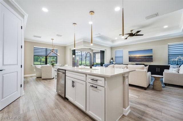 kitchen with ceiling fan with notable chandelier, sink, pendant lighting, white cabinetry, and an island with sink