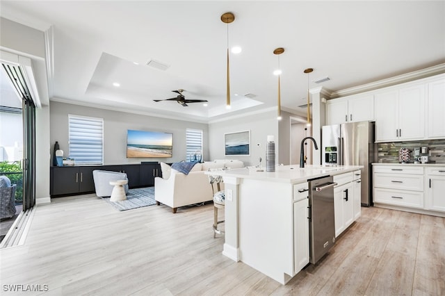 kitchen with a center island with sink, open floor plan, decorative light fixtures, light countertops, and white cabinetry