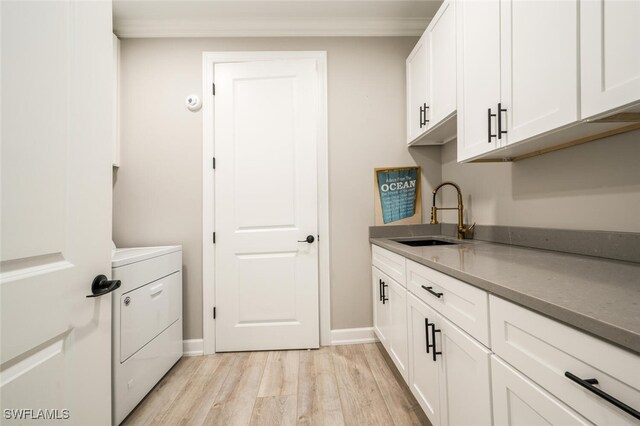 clothes washing area with cabinets, ornamental molding, sink, light hardwood / wood-style flooring, and washer / clothes dryer