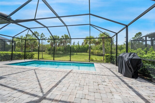 view of swimming pool with glass enclosure, a patio area, and area for grilling