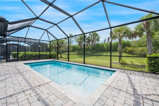 view of pool featuring a lawn, glass enclosure, and a patio