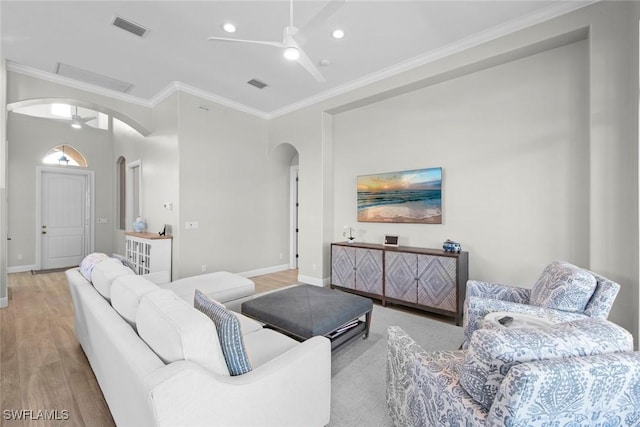 living room featuring crown molding, ceiling fan, and light wood-type flooring