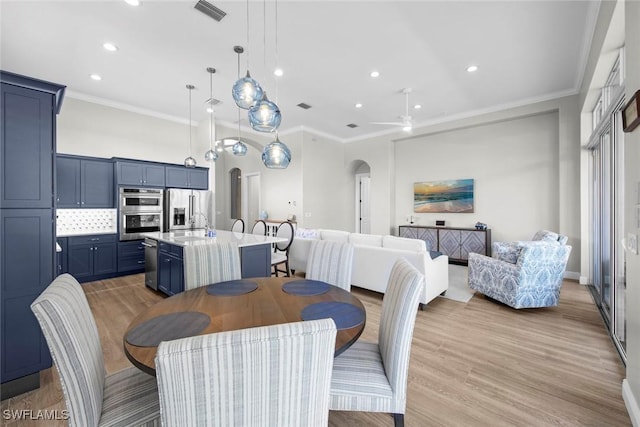 dining space featuring sink, ornamental molding, light hardwood / wood-style floors, and ceiling fan