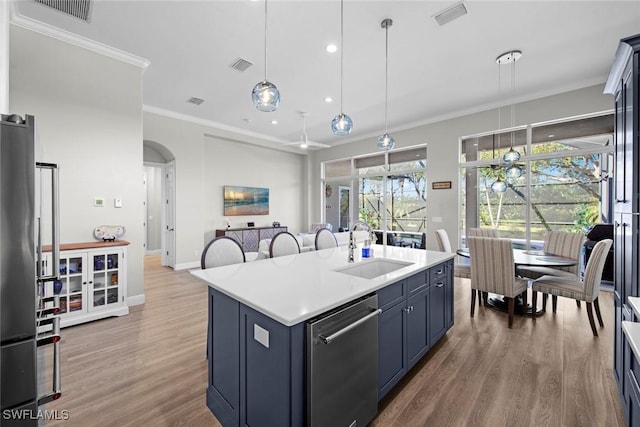 kitchen featuring sink, hardwood / wood-style flooring, a kitchen island with sink, stainless steel appliances, and decorative light fixtures