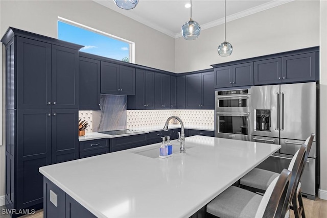 kitchen with a breakfast bar, sink, hanging light fixtures, a center island with sink, and appliances with stainless steel finishes