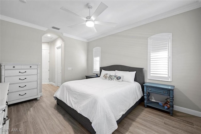 bedroom with ceiling fan, ornamental molding, hardwood / wood-style floors, and multiple windows