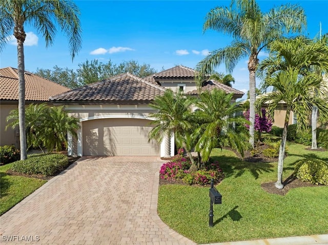 mediterranean / spanish house with stucco siding, decorative driveway, an attached garage, and a tiled roof